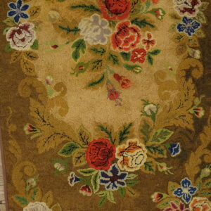 Textured floral rug with red and blue blooms framed by a brown border on light wood floor.