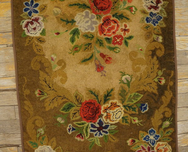 Textured floral rug with red and blue blooms framed by a brown border on light wood floor.