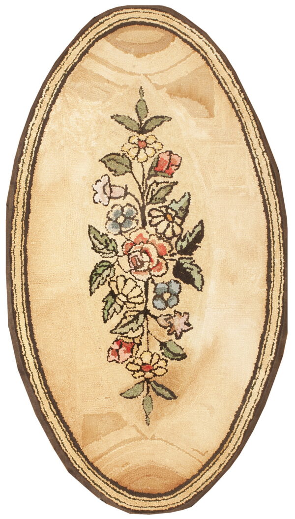 Oval tan rug featuring a central multicolored floral vine and a dark brown striped border.