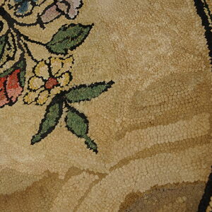 Textured tan rug detail with pink, yellow, and green floral motifs and a black striped outer border.