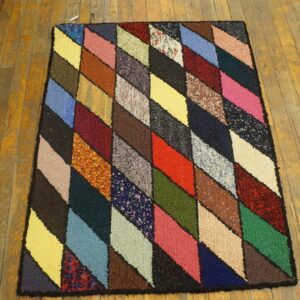 High-texture rug featuring a multicolored diamond geometric pattern on distressed amber wood flooring.