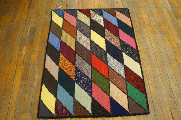High-texture rug featuring a multicolored diamond geometric pattern on distressed amber wood flooring.