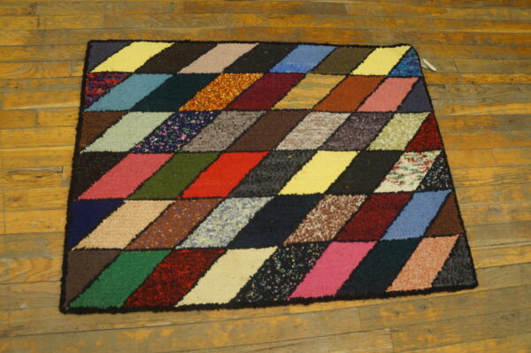 Multicolored high-pile rug featuring a diamond geometric pattern resting on distressed yellow wood planks.