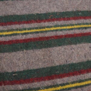 Fuzzy, low-pile gray rug with bold horizontal stripes of green, red, and yellow on wood plank flooring.