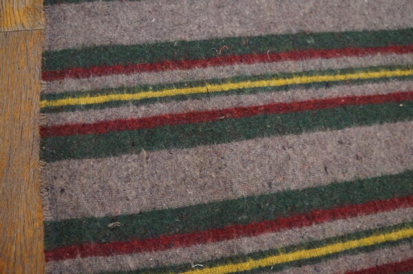 Fuzzy, low-pile gray rug with bold horizontal stripes of green, red, and yellow on wood plank flooring.