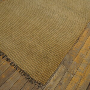Textured tan and dark striped rug featuring fringe, displayed on weathered golden hardwood flooring.