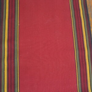 A solid red rug runner with dark multicolored border stripes rests on light hardwood floors.