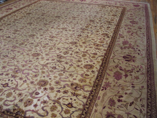 Cream rug with an elaborate traditional floral pattern in mauve and brown, displayed on a wood floor.