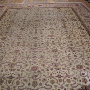 Large beige traditional rug with an elaborate purple and brown floral vine pattern on a wood floor.