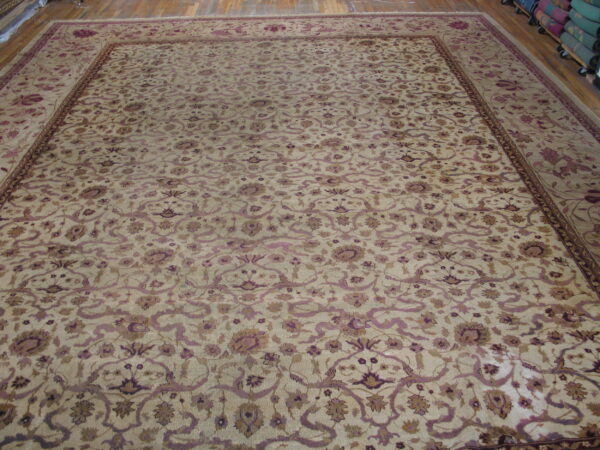 Large beige traditional rug with an elaborate purple and brown floral vine pattern on a wood floor.