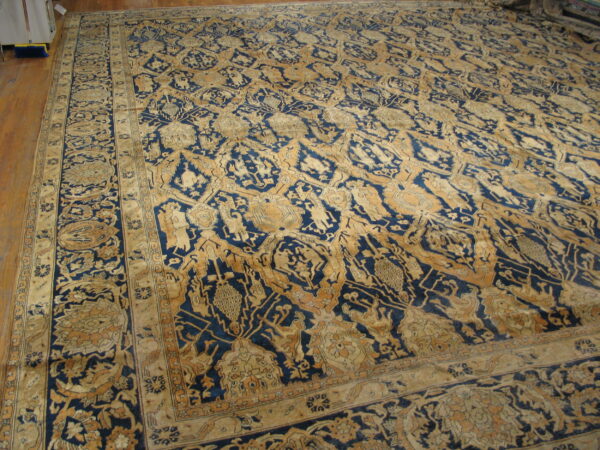 Ornate indigo and tan rug featuring complex repeating patterns on a hardwood floor.