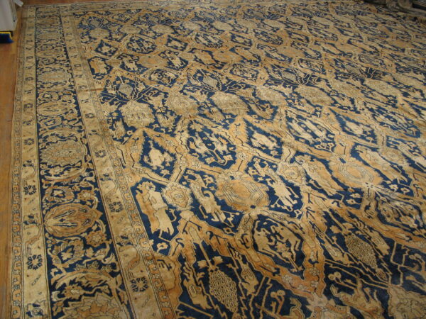 Intricate blue and gold traditional rug displaying stylized patterns and borders on wood flooring.