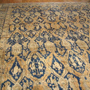 Ornate indigo and gold rug featuring complex repeating patterns and stylized figures on wood floors.