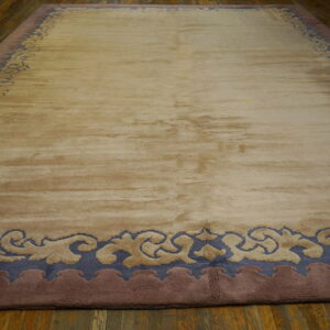 Large beige rug with a slate blue and mauve curvilinear border rests on a wooden floor.