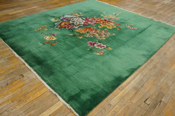 Plush green rug with vibrant central floral and butterfly pattern rests on worn hardwood flooring.