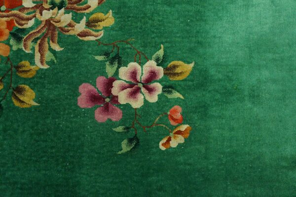 Green plush rug detail showing floral elements in pink, cream, maroon, and golden-yellow.