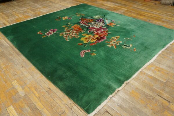 Plush green rug featuring an asymmetrical colorful floral design on yellowish wood planks.