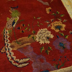 Red rug features large floral and pheasant designs in green, purple, and gold on worn wood planks.