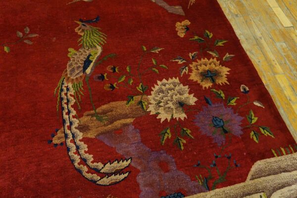 Red rug features large floral and pheasant designs in green, purple, and gold on worn wood planks.