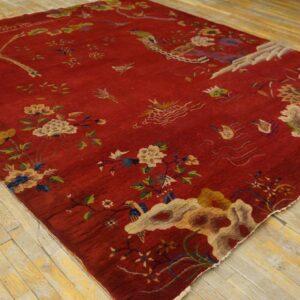 Deep red pictorial rug with multi-colored flowers and birds resting on light wooden plank flooring.