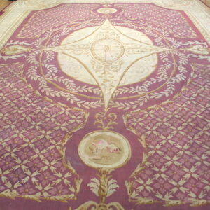 Large rose and cream rug featuring an elaborate central medallion and repeating floral field patterns on wood flooring.