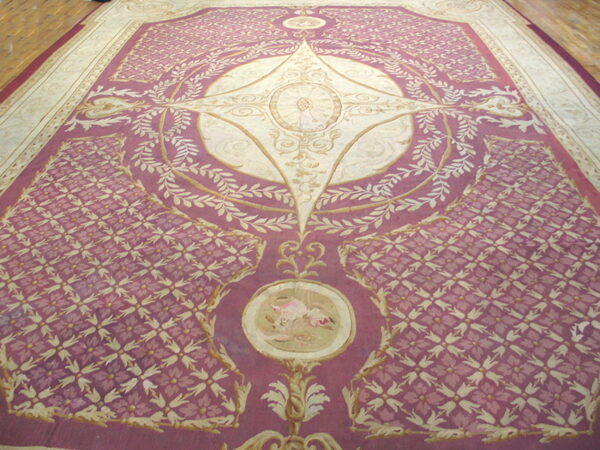 Large rose and cream rug featuring an elaborate central medallion and repeating floral field patterns on wood flooring.