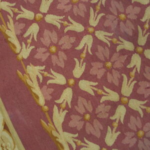 Stylized gold and pink floral patterns cover a maroon textile with a distinct scrolling border.
