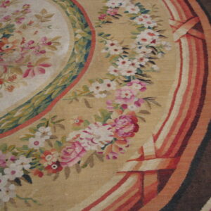 Detailed flatweave rug with a floral pattern, pale gold field, red ribbons, and a dark brown border.