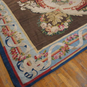 Dark brown and blue flat-weave rug with ornate floral patterns displayed on a hardwood floor.