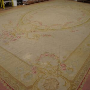 Large low pile cream rug featuring pink and gold ornate floral patterns on a dark wood floor.