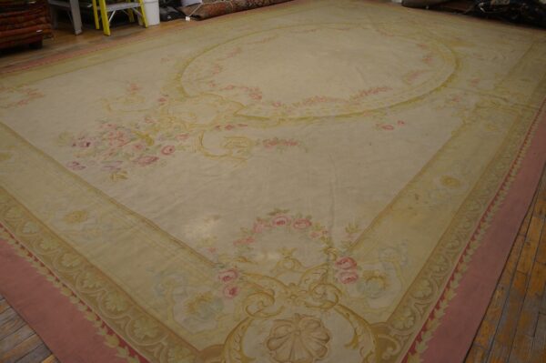 Large low pile cream rug featuring pink and gold ornate floral patterns on a dark wood floor.