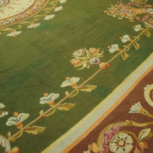 Detailed view of a classic rug featuring a green field, colorful floral motifs, and a wide rust-colored border.
