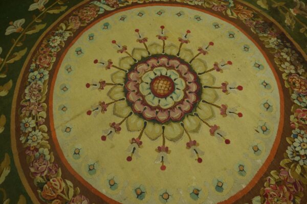 Low-pile floral rug featuring a central medallion on a pale yellow field and wide green and brown floral borders.