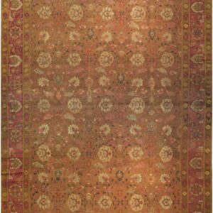 Rust orange rug featuring a dense floral pattern and a wide border of rose and gold tones.