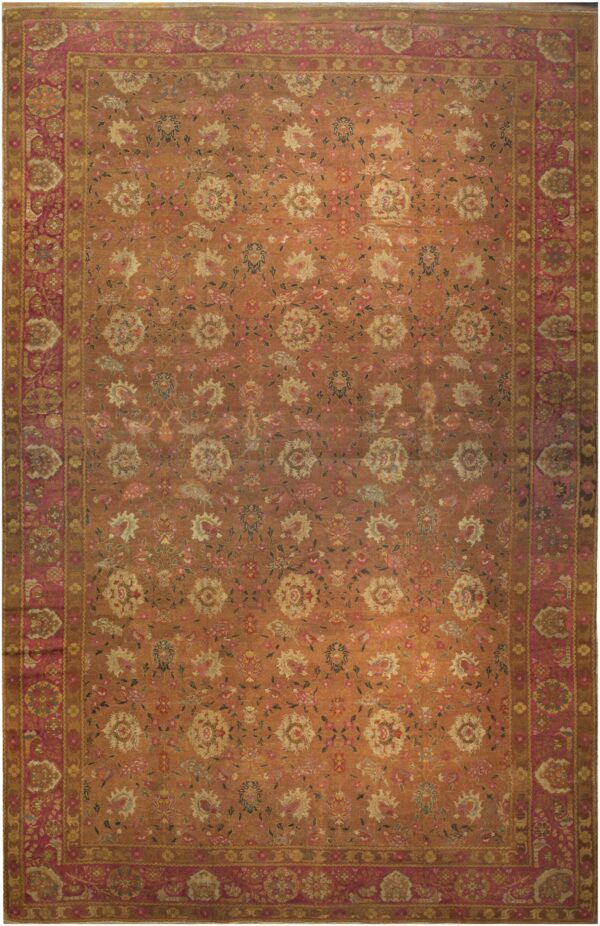 Rust orange rug featuring a dense floral pattern and a wide border of rose and gold tones.