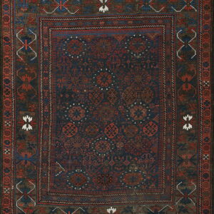 Dark navy rug with repeating rust red geometric motifs framed by a complex multicolored border.