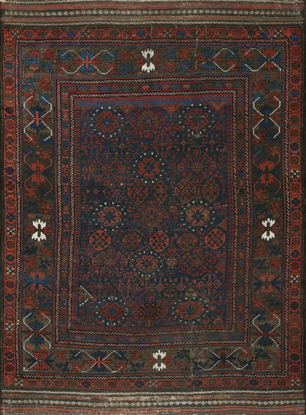 Dark navy rug with repeating rust red geometric motifs framed by a complex multicolored border.