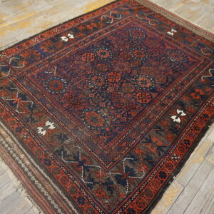 Geometric rug in deep blue and terracotta, featuring a complex border, resting on worn wood planks.