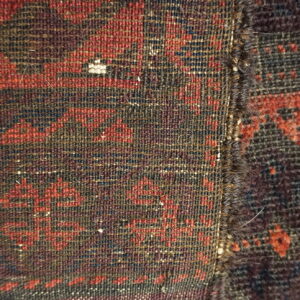 Two contrasting dark red and brown geometric rug textures meet at a tightly bound, vertical edge.