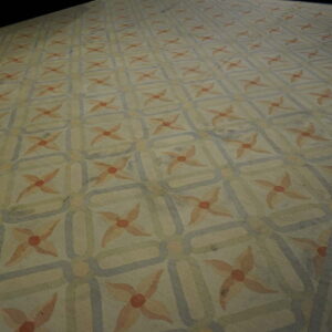Cream and muted blue rug with a geometric grid pattern containing light orange floral starbursts.