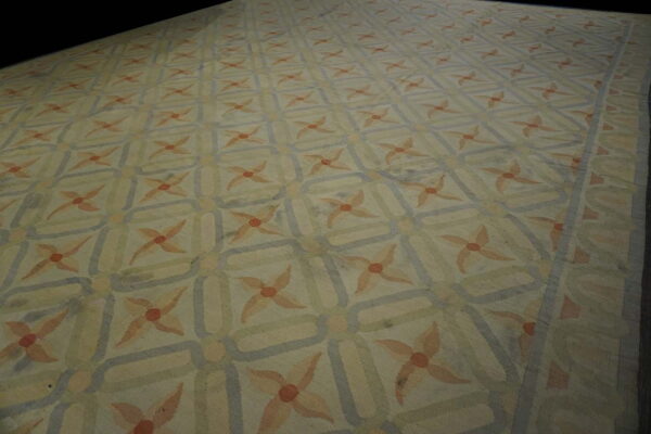 Cream and muted blue rug with a geometric grid pattern containing light orange floral starbursts.