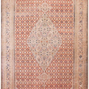 Muted traditional rug with a large central medallion, an all-over red geometric field, and wide beige borders.