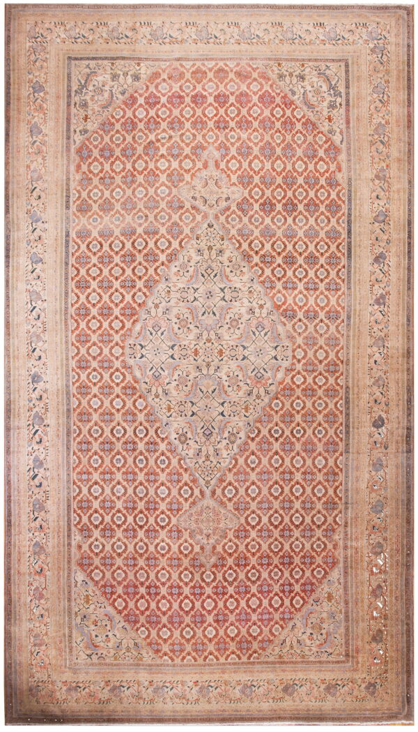 Muted traditional rug with a large central medallion, an all-over red geometric field, and wide beige borders.