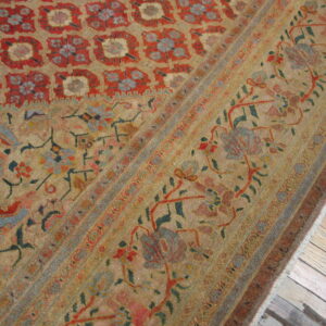 Low-pile rug with a complex red, gold, and blue traditional pattern rests on rustic wood planks.