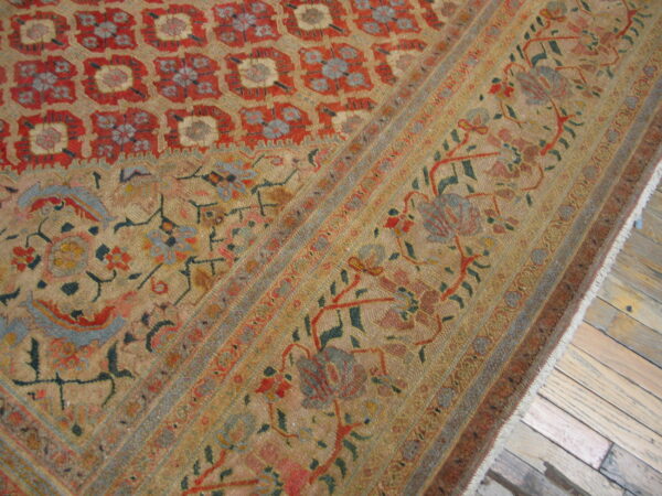 Low-pile rug with a complex red, gold, and blue traditional pattern rests on rustic wood planks.