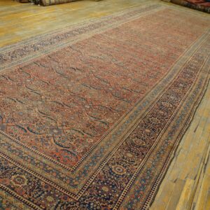 A long, intricate rug with rust, navy, and cream floral patterns lies on glossy golden wood flooring.