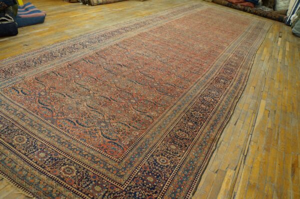 A long, intricate rug with rust, navy, and cream floral patterns lies on glossy golden wood flooring.