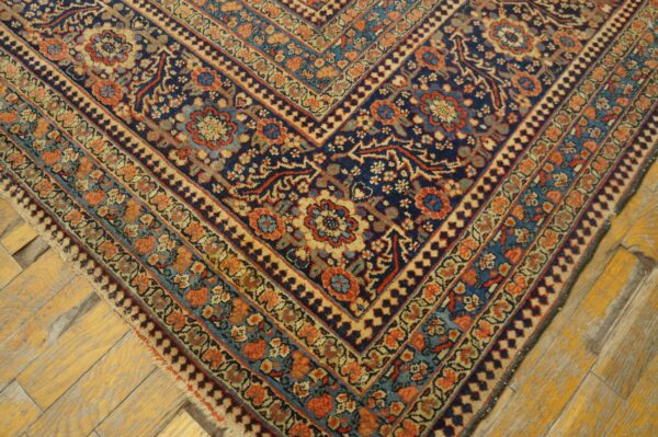 Intricate floral and geometric blue, rust, and beige rug section on aged wooden floorboards.