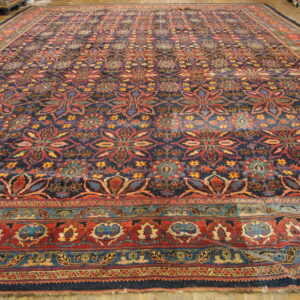 Ornate, large blue rug with repeating red, yellow, and teal floral medallions on light wood flooring.