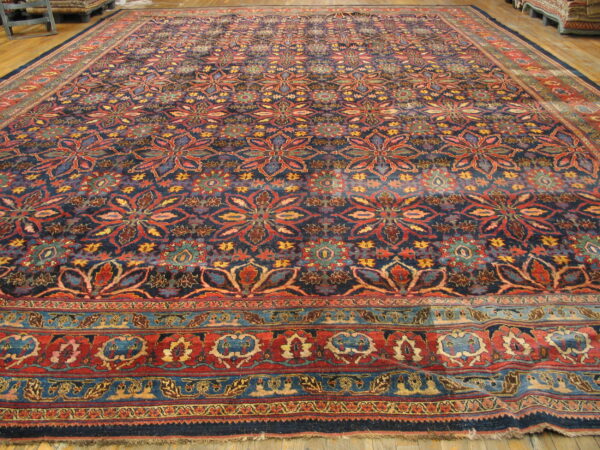 Ornate, large blue rug with repeating red, yellow, and teal floral medallions on light wood flooring.